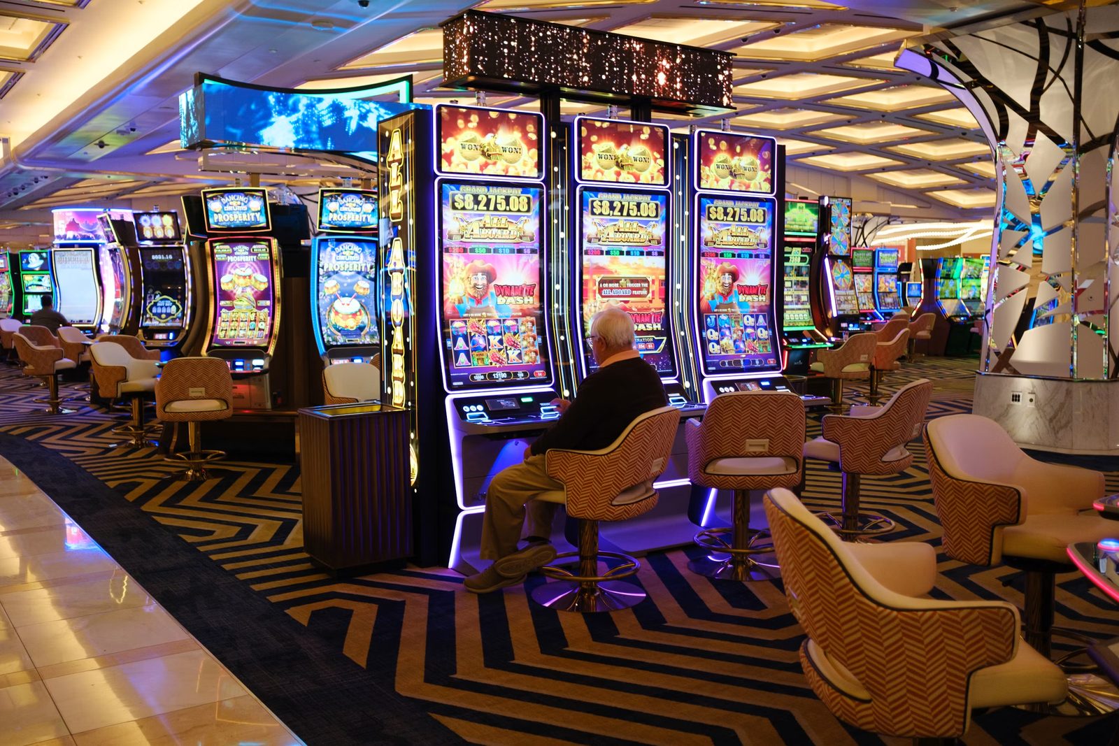 Row of glowing 777 slot machines in a golden casino hall